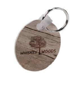 Custom round keychain with wooden texture design featuring the text 'WHISKEY WOODS' and a metal ring.
