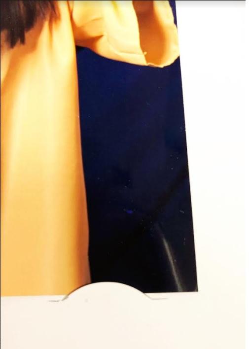 Close-up of a photo in a cardboard easel frame showing yellow fabric and a black background.