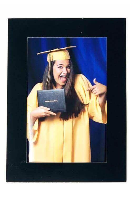 Graduation photo displayed in a glossy black cardboard easel, showcasing a cheerful graduate holding a diploma.