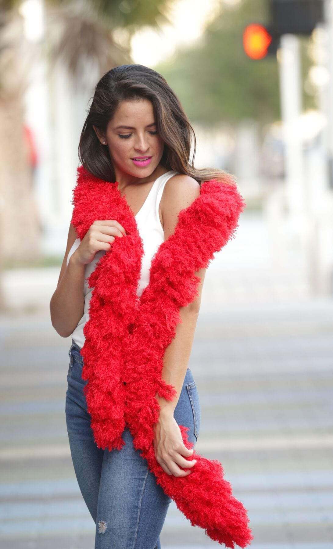 Woman wearing a vibrant red supersized featherless boa on the street, showcasing its fun and stylish design.